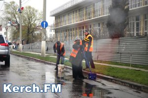 В Керчи под дождем рабочие моют бордюры